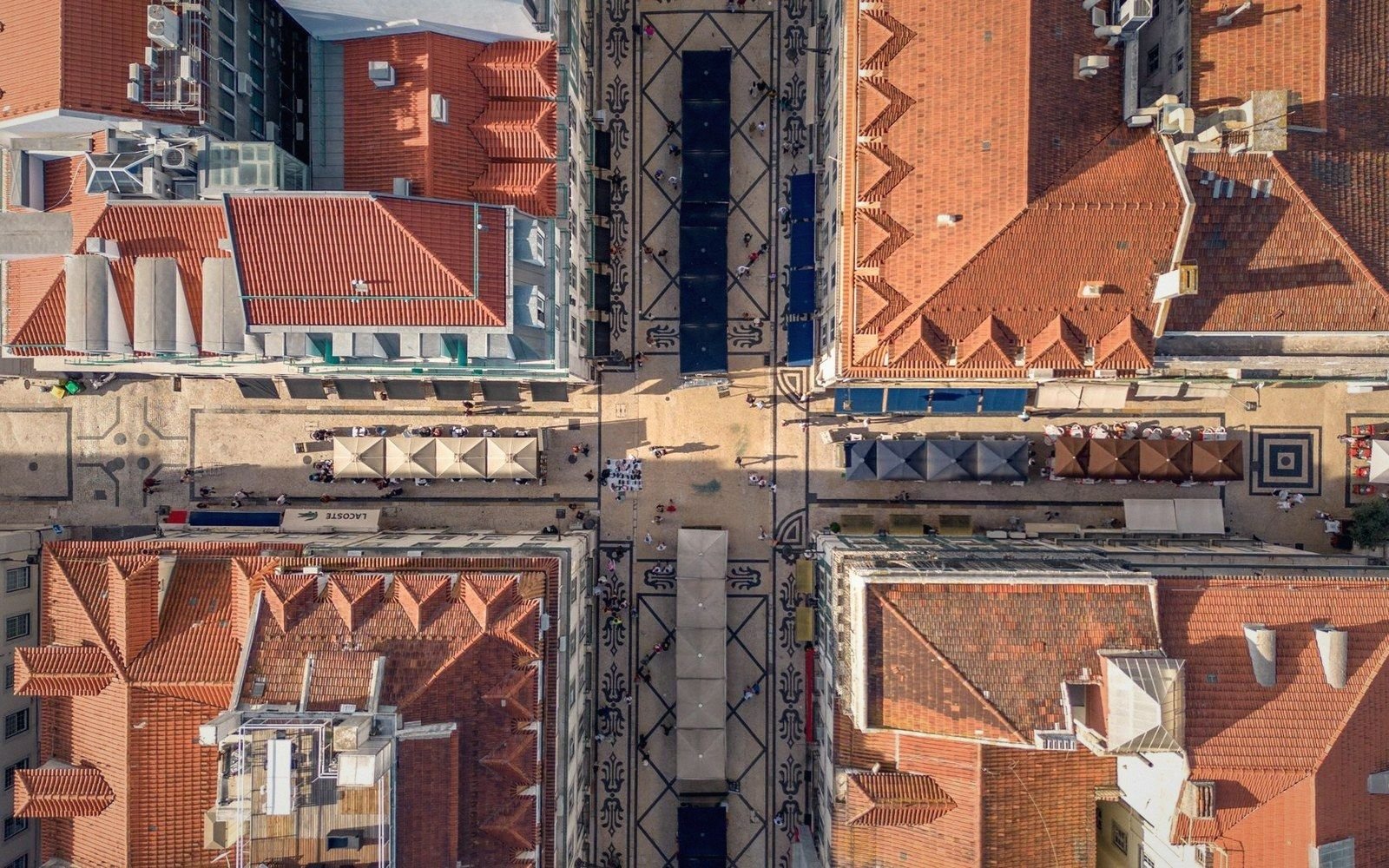 Aerial view of a crossroads lined with red-tiled rooftops and market stalls below