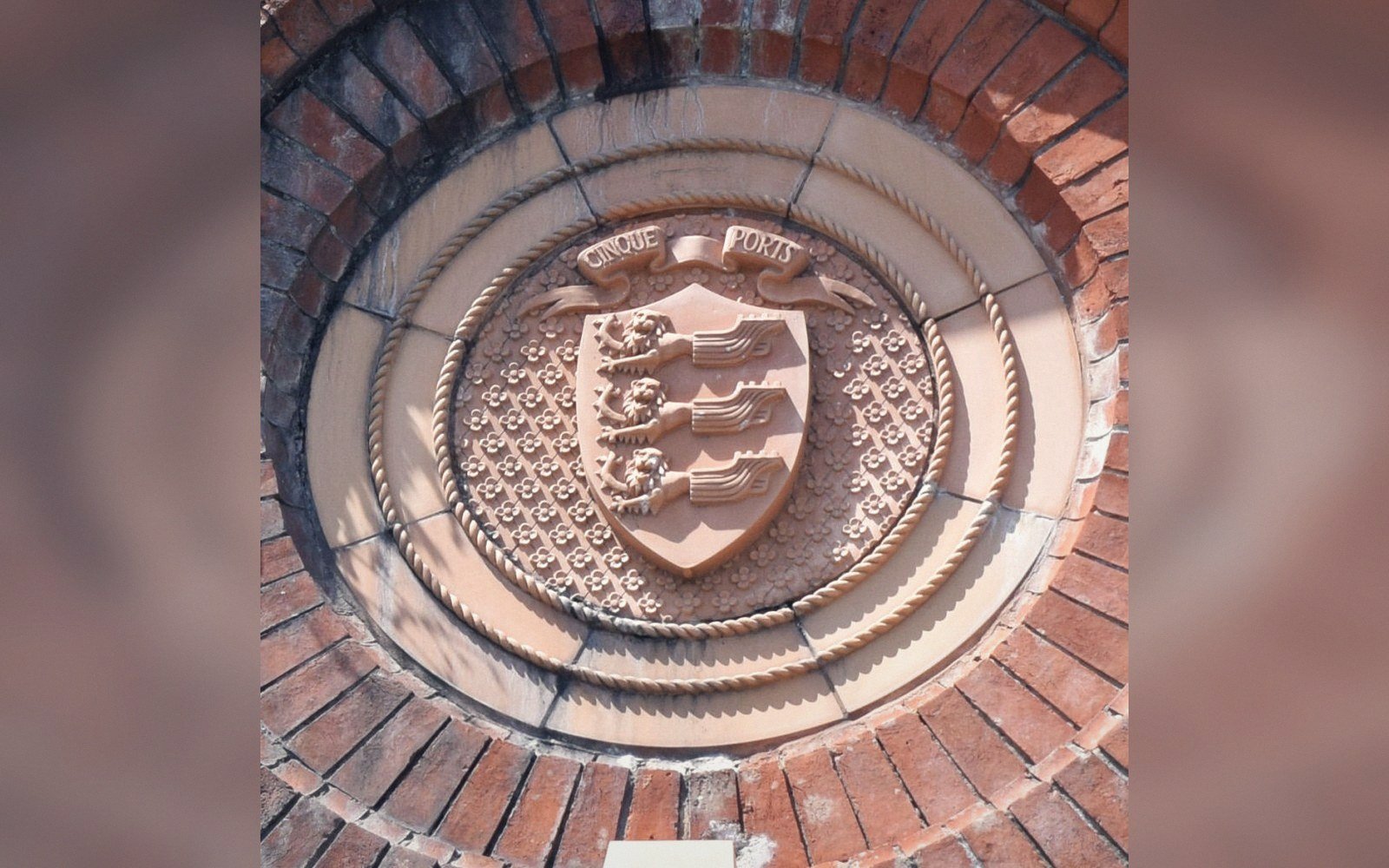Carved stone roundel showing the Cinque Ports coat of arms set into a brick wall