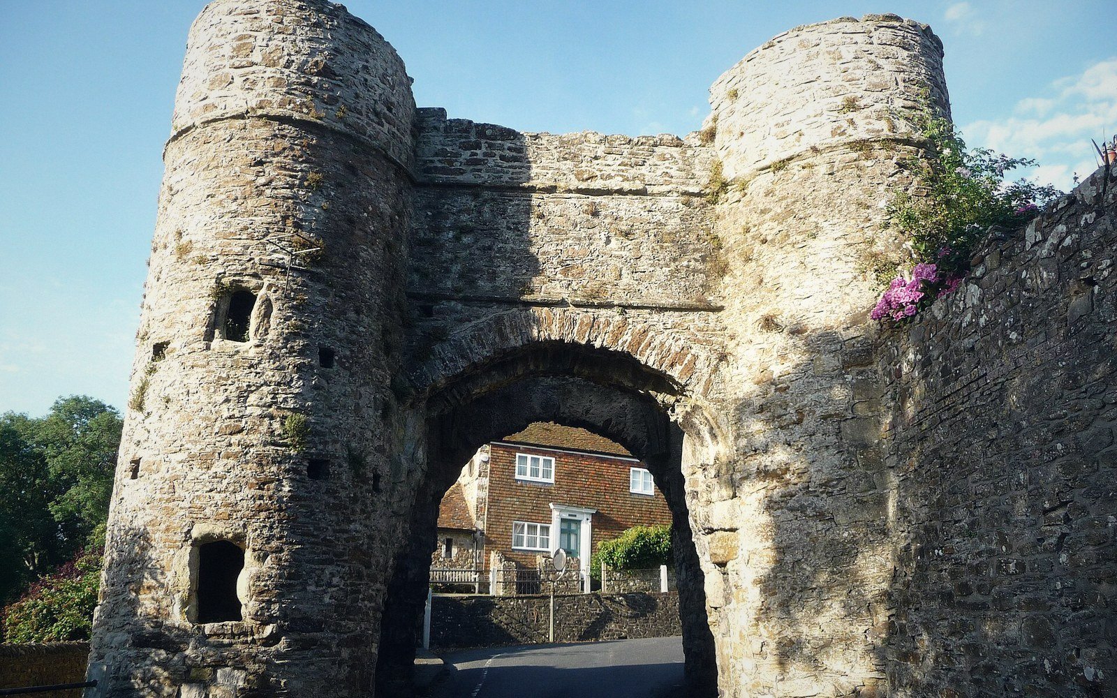 A medieval stone gate arch standing alone in open grass with no wall attached